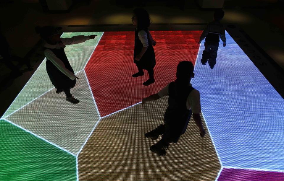 Children run across an interactive exhibit at the new National Museum of Mathematics in New York, Monday, Dec. 17, 2012. The museum is aimed at kids aged 8 to 13, and curators have given the place a playground feel. The 40 exhibits include a "wall of fire" made up of laser lights that teaches kids about geometry and a square-wheeled tricycle that still manages to produce a smooth ride thanks to a wavy track. (AP Photo/Seth Wenig)
