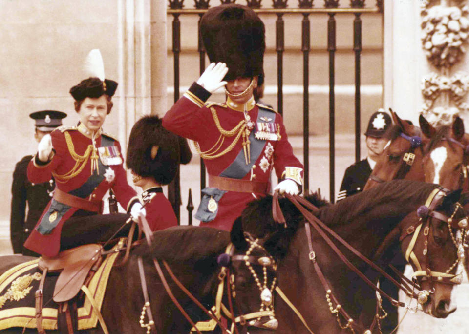 ARCHIVO - En esta foto del 14 de junio de 1975, la reina Isabel II de Inglaterra y su esposo, el príncipe Felipe, saludan a caballo frente a las puertas del Palacio de Buckingham en Londres, tras la ceremonia anual Trooping of the Color. (AP Foto/Horst Faas, Archivo)
