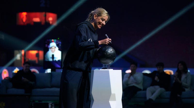 The streamer Gemita signs a black soccer ball during the Queens League reveal.