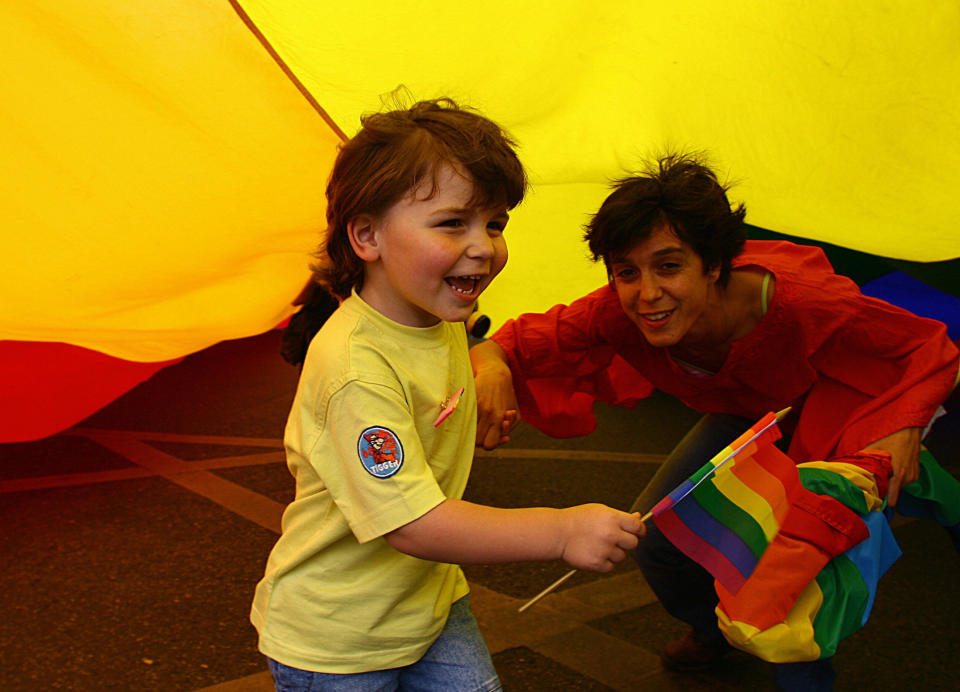 A mother and child play under a giant rainbow flag during the Gay Pride parade in downtown Lisbon&nbsp;on June 24,&nbsp;2006. AFP PHOTO/ FRANCISCO LEONG