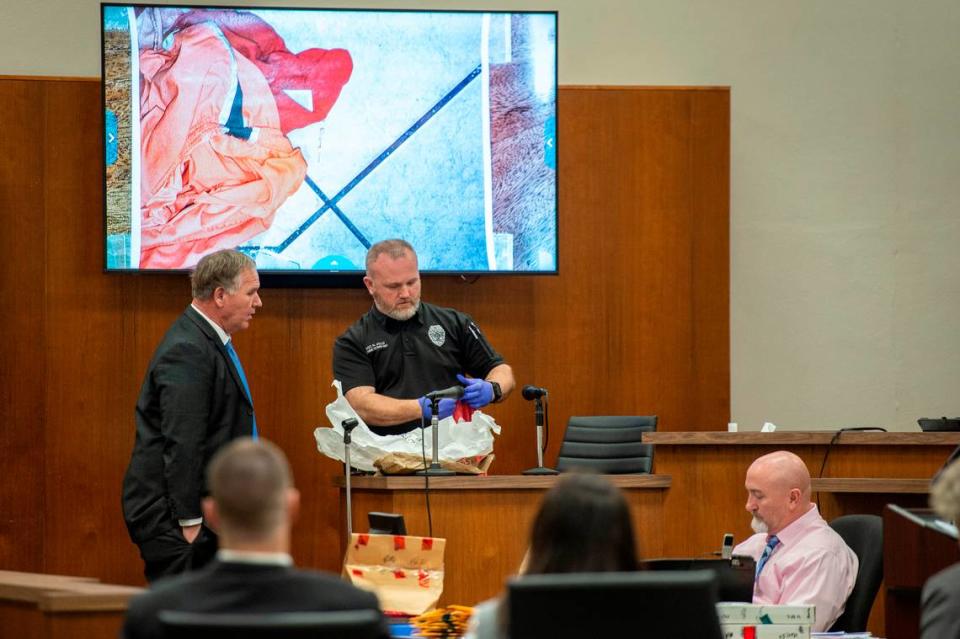 Sgt. Robert Jolly, center, examines a piece of evidence and compares it to a photograph taken at the scene of the murder of Penny Clark while he is on the witness stand during trial at Harrison County Circuit Court in Biloxi on Tuesday, March 8, 2022.