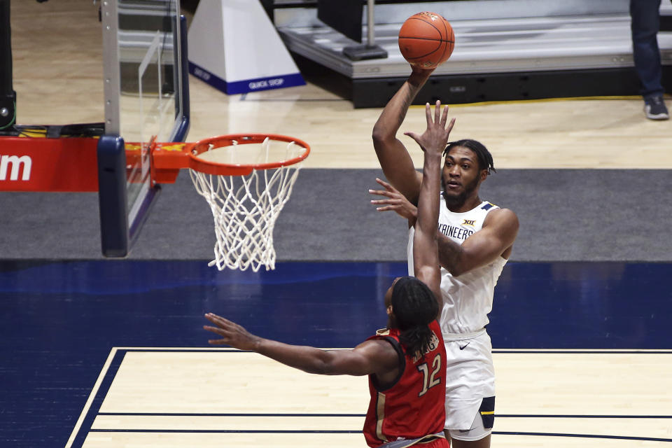 West Virginia forward Derek Culver (1) shoots while defended by Northeastern forward Alex Nwagha (12) during the first half of an NCAA college basketball game Tuesday, Dec. 29, 2020, in Morgantown, W.Va. (AP Photo/Kathleen Batten)