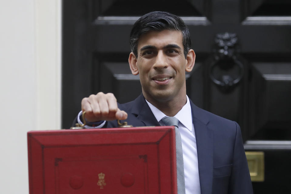 Britain's Chancellor of the Exchequer Rishi Sunak stands outside No 11 Downing Street and holds up the traditional red box that contains the budget speech for the media, he will then leave to make budget speech to House of Commons, in London, Wednesday, March 11, 2020. Britain's Chancellor of the Exchequer Rishi Sunak will announce the first budget since Britain left the European Union. (AP Photo/Kirsty Wigglesworth)