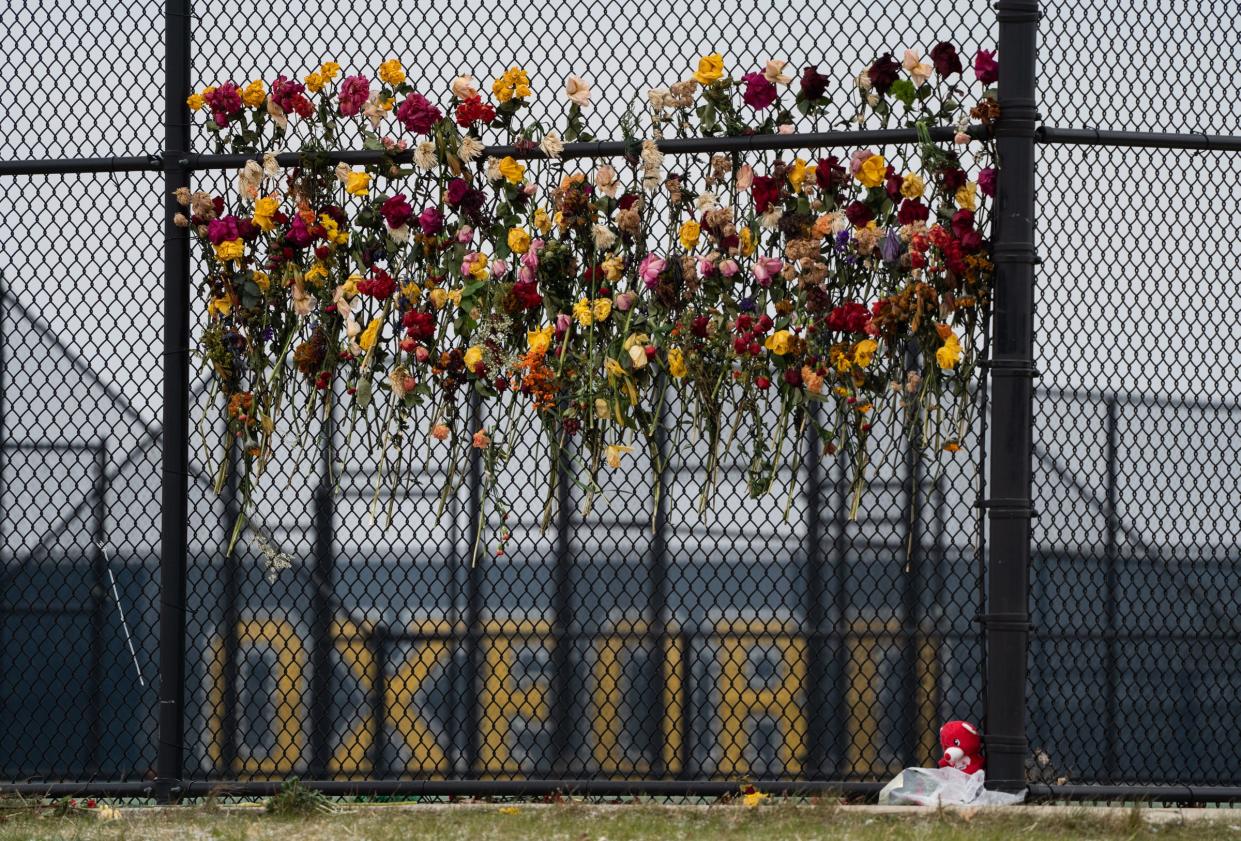 Flowers are attached to the fence outside of the tennis courts at Oxford High School on Thursday, December 9, 2021, as a memorial in memory of the four students shot and killed and multiple others after a classmate opened fire during an active shooter at Oxford High School.