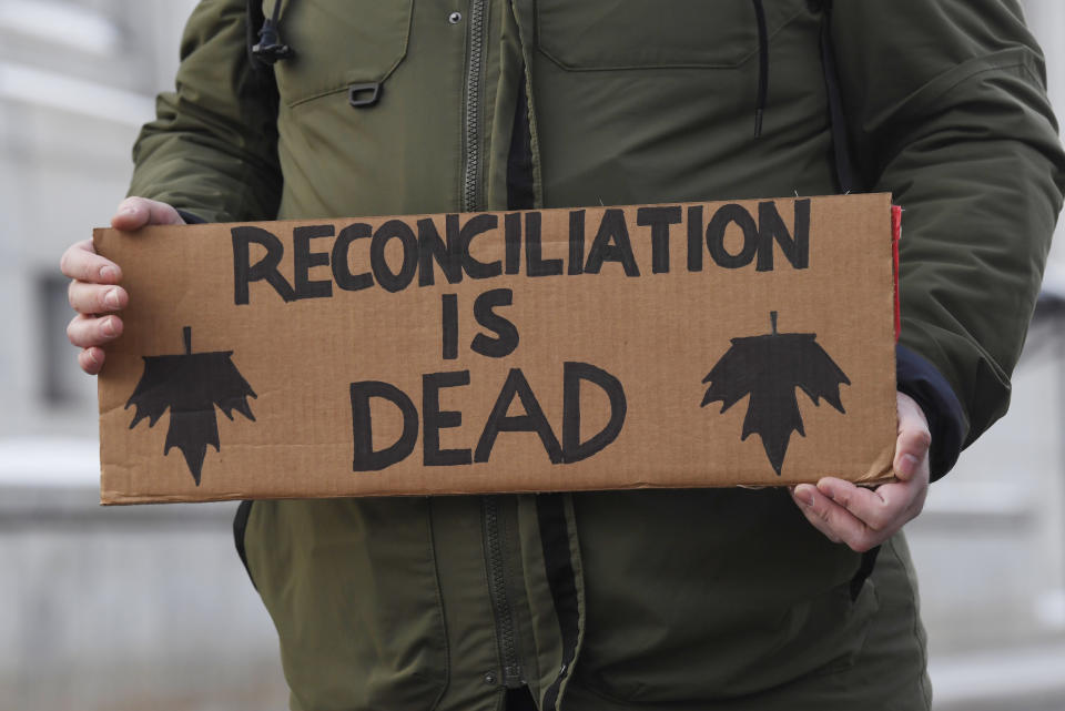 A protester carries a sign as he and others were marching on a street in Ottawa, Ontario, Wednesday, Feb. 12, 2020. The protesters are standing in solidarity with the Wet'suwet'en hereditary chiefs opposed to a Canada gas pipeline in northern British Columbia. (Adrian Wyld/The Canadian Press via AP)