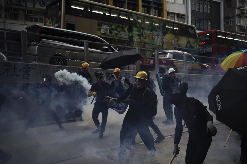 Protesters face police tear smoke in Hong Kong, Sunday, Oct. 20, 2019. Hong Kong protesters again flooded streets on Sunday, ignoring a police ban on the rally and demanding the government meet their demands for accountability and political rights. (AP Photo/Felipe Dana)