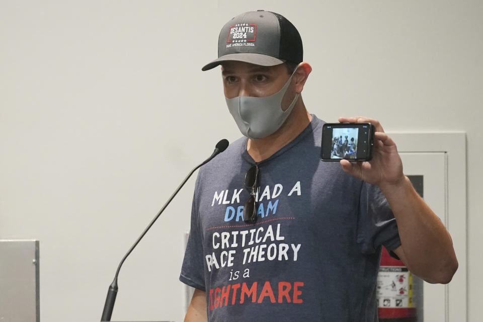 Elon Gerberg holds up a picture of his two young children singing and dancing at a private daycare, during the Broward School Board's emergency meeting, Wednesday, July 28, 2021, in Fort Lauderdale, Fla. The board listened to parents' concerns and will make a decision regarding the use of masks for K-12 students in the upcoming school year. (AP Photo/Marta Lavandier)