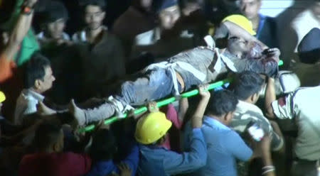 ATTENTION EDITORS - VISUAL COVERAGE OF SCENES OF DEATH OR INJURY Policemen and rescue workers carry an injured man to an ambulance after a four-story hotel collapsed in a crowded part of the central Indian city of Indore late on Saturday, in this still image taken from video released on April 1, 2018. ANI/via REUTERS TV