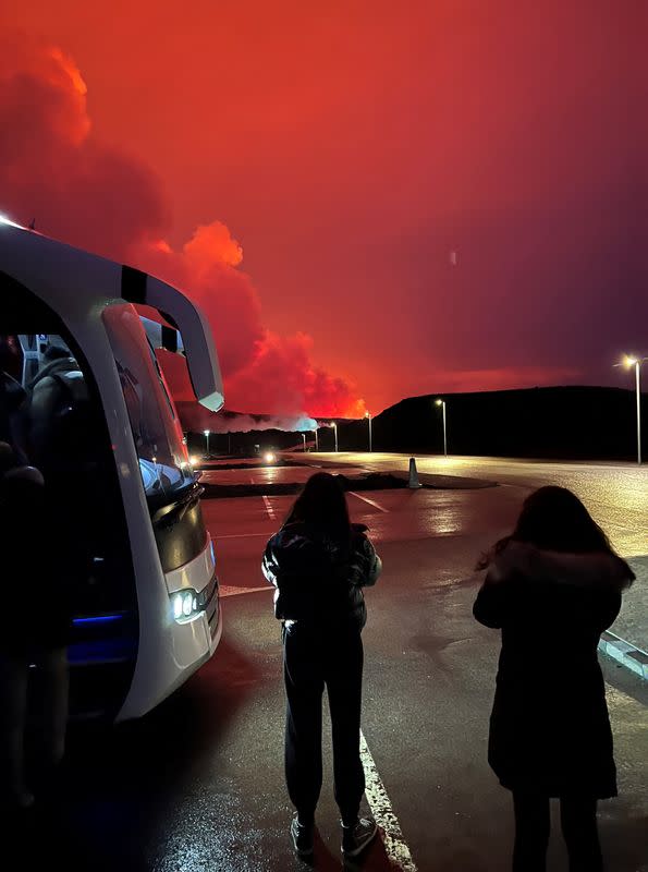 Personas que están siendo evacuadas permanecen junto. a un autobús mientras un volcán entra en erupción, en Grindavik, Islandia, el 16 de marzo de 2024, en esta imagen obtenida de las redes sociales