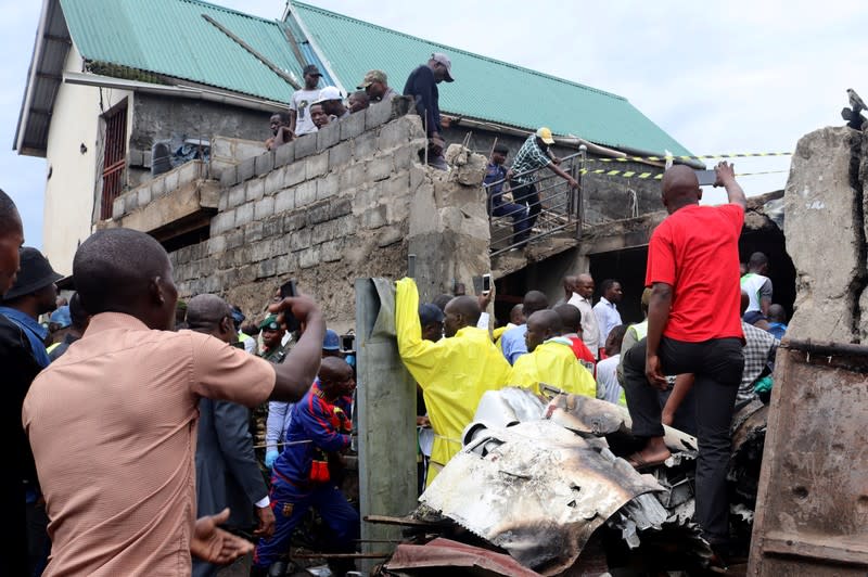 Rescuers and civilians gather at the site where a Dornier 228-200 plane operated by local company Busy Bee crashed into a densely populated neighborhood in Goma