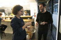 In this Tuesday, Nov. 5, 2019 photo, Anne-Marie McGonnigal, left, with South Pole, and Lanny Grossman, owner of public relations firm EM50 Communications, exchange business cards at a WeWork office space, in New York. WeWork is slashing the lavish spending that has fueled its breakneck growth while racking up unsustainable losses. Experts are skeptical that the office-sharing company can achieve meaningful cost reductions without somehow squeezing tenants. (AP Photo/Mark Lennihan)