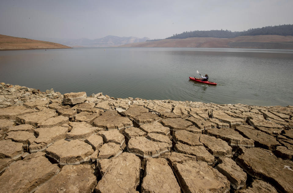 FILE - A kayaker paddles in Lake Oroville as water levels remain low due to continuing drought conditions in Oroville, Calif., Sunday, Aug. 22, 2021. Administration officials from California said they hope to demonstrate at the United Nation's climate change conference in Glasgow that tackling the climate crisis can be good for the economy and that pollution targets should be made with historically underserved communities in mind. (AP Photo/Ethan Swope, File)