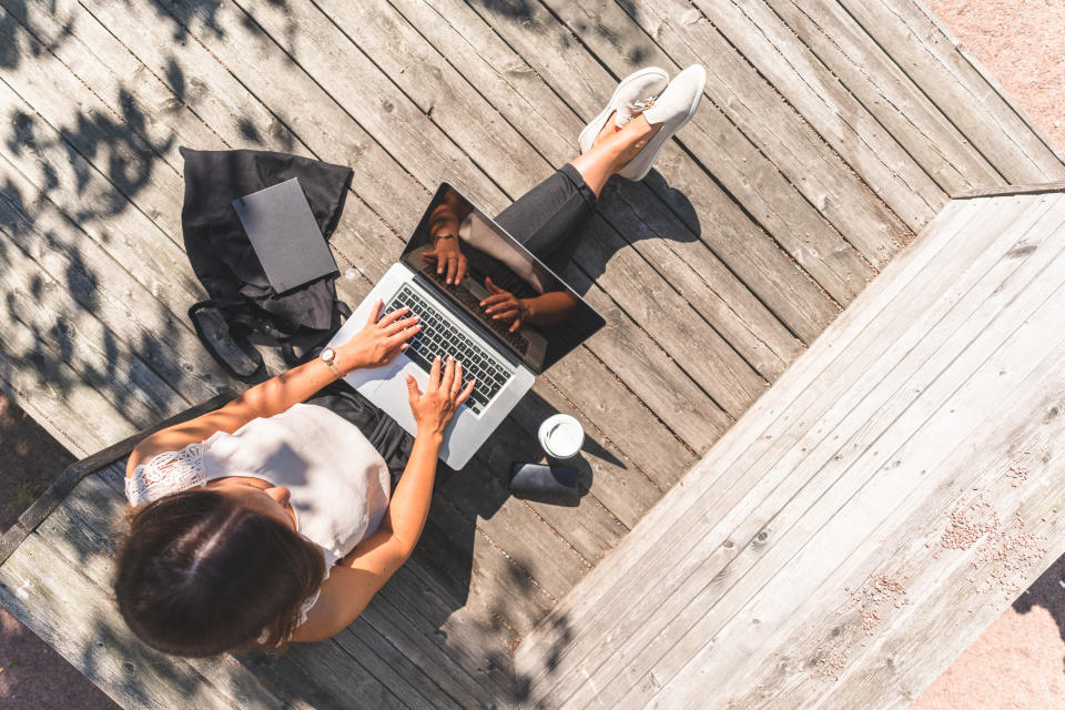 A woman with a smart phone and a laptop is working on the go thanks to the freedom of freelance work.