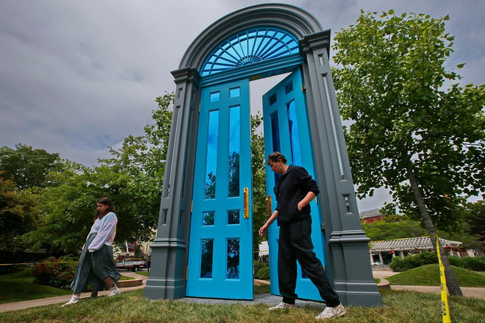 Lindsay Mis, Executive Director of DATMA inspects the area around the just installed seventeen foot tall doorway art piece 'Threshold' installed at Custom House Square in New Bedford.