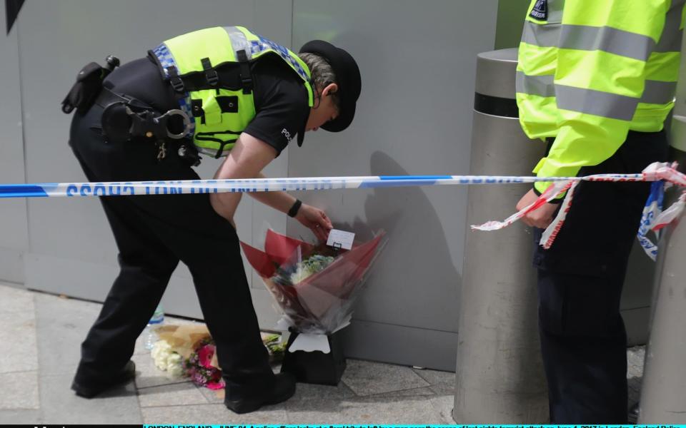 A police officer looks at a floral tribute left by a man near the scene - Credit: Christopher Furlong/Getty Images