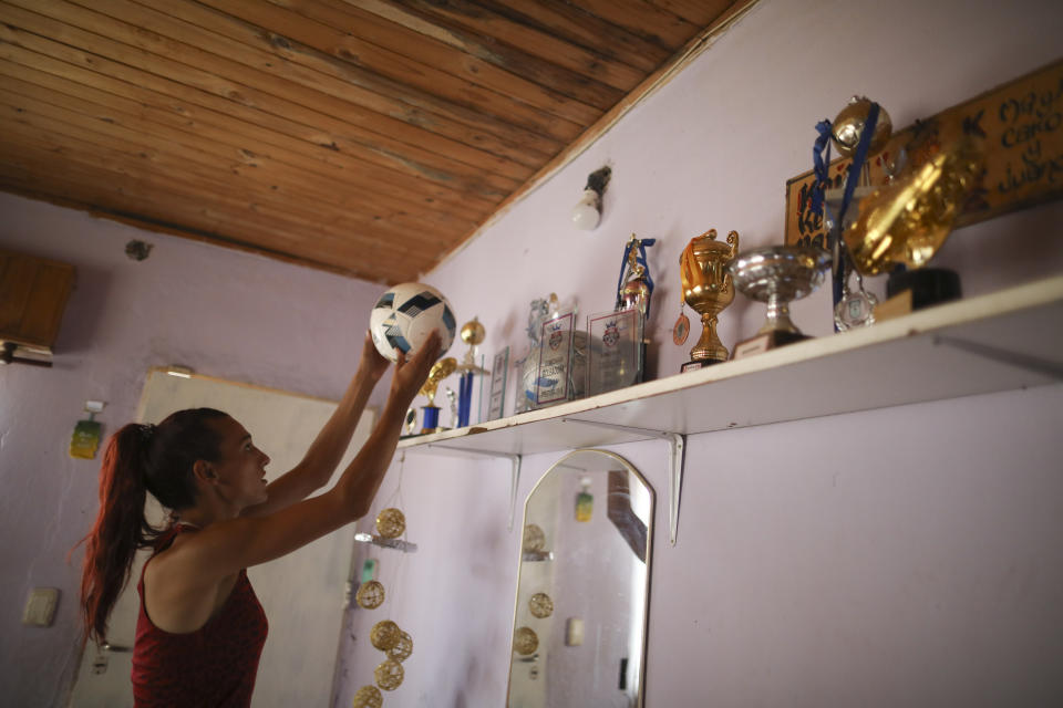 Soccer player Mara Gomez puts a ball back on the shelf full of her soccer trophies at her home in La Plata, Argentina, Thursday, Feb. 6, 2020. Gomez is a transgender woman who is limited to only training with her women's professional soccer team, Villa San Carlos, while she waits for permission to start playing from the Argentina Football Association (AFA). If approved, she would become the first trans woman to compete in a first division, professional Argentine AFA tournament. (AP Photo/Natacha Pisarenko)