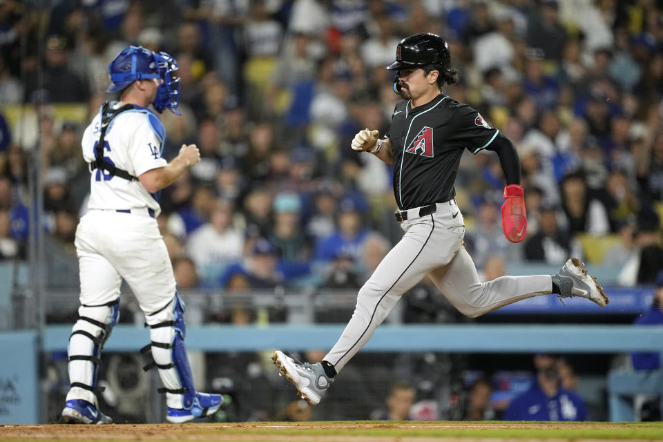 Arizona Diamondbacks' Corbin Carroll, right, scores on a wild pitch as Los Angeles Dodgers catcher Will Smith stands at the plate during the fifth inning of a baseball game Wednesday, May 22, 2024, in Los Angeles. (AP Photo/Mark J. Terrill)