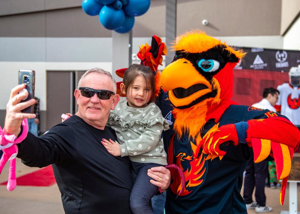 Don Davis of La Quinta and 4-year-old Riley Kim take a photo with Fuego, the Firebirds mascot, during the Firebirds fan fest at Acrisure Arena in Palm Desert, Calif., Saturday, Dec. 17, 2022. 