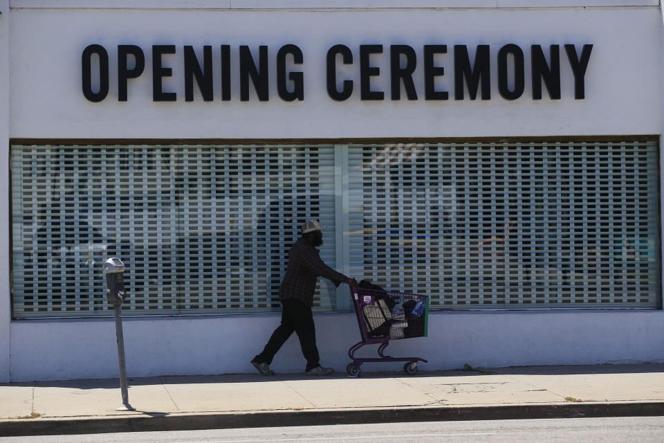 A homeless walks past the closed down "Opening Ceremony" fashion store in Los Angeles Friday, May 8, 2020. Throughout California, there has been an on-again, off-again patchwork of enforcement on everything from business closures to wearing face masks. It's fallen to local officials to both interpret and enforce rapidly evolving rules, with state and local orders often at odds. The confusion is likely to continue after Newsom outlined more guidelines Thursday for local governments to follow as they allow businesses to reopen. (AP Photo/Damian Dovarganes)