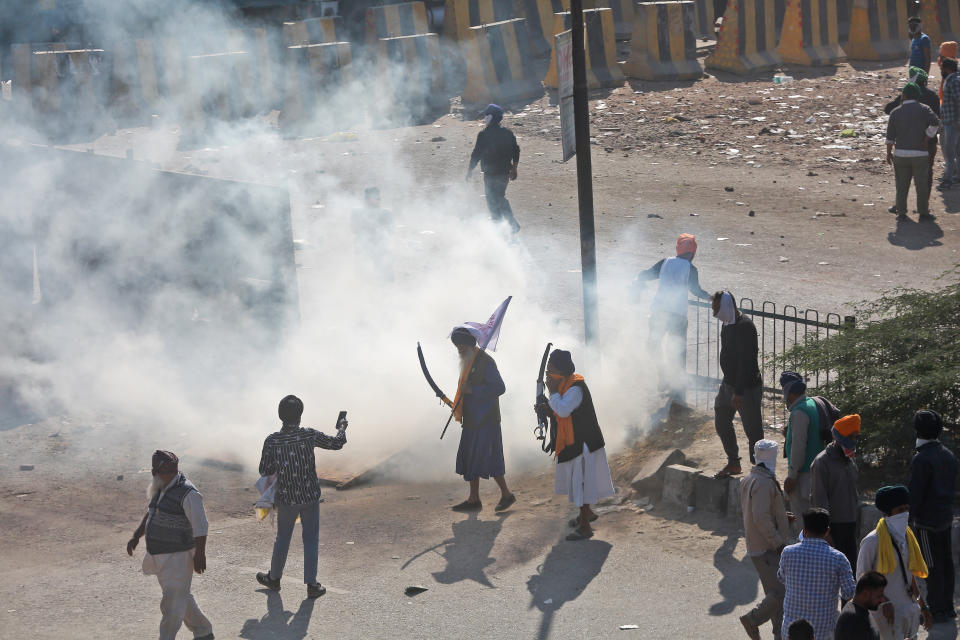 A tear gas shell explodes bear protesting farmers as security officers prevent them from moving towards Delhi, at the border between Delhi and Haryana state, Friday, Nov. 27, 2020. Thousands of agitating farmers in India faced tear gas and baton charge from police on Friday after they resumed their march to the capital against new farming laws that they fear will give more power to corporations and reduce their earnings. While trying to march towards New Delhi, the farmers, using their tractors, cleared concrete blockades, walls of shipping containers and horizontally parked trucks after police had set them up as barricades and dug trenches on highways to block roads leading to the capital. (AP Photo)