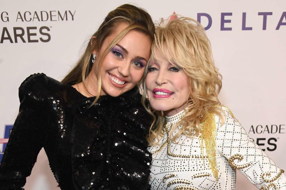 <p>Kevin Mazur/Getty </p> Miley Cyrus and Dolly Parton in Los Angeles in February 2019