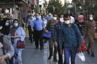 People wearing protective face masks to help prevent spread of the coronavirus walk on a sidewalk of a commercial street in Tehran, Iran, Sunday, Sept. 20, 2020. Iran's president dismissed U.S. efforts to restore all U.N. sanctions on the country as mounting economic pressure from Washington pushed the local currency down to its lowest level ever on Sunday. (AP Photo/Vahid Salemi)