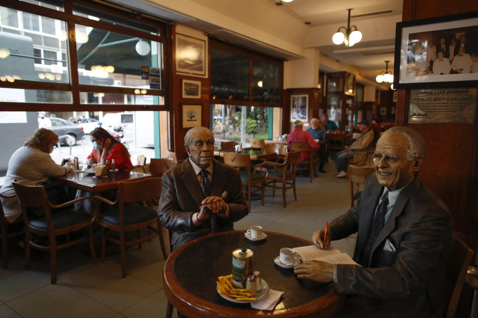 Statues of Argentine writer Adolfo Bioy Casares, right, and Jorge Luis Borges, sit at a table at La Biela restaurant in Buenos Aires, Argentina, Tuesday, Nov. 10, 2020. At least four of the city’s more than 70 officially recognized “cafe notables” have closed since a quarantine to curb the spread of the new coronavirus was announced on March 20 and others are hanging by a thread after months of revenues near zero. (AP Photo/Natacha Pisarenko)