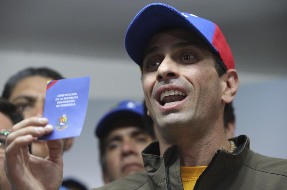 El líder opositor Henrique Capriles muestra una copia de la constitución de Venezuela durante una conferencia de prensa en Caracas, el jueves 6 de abril de 2017. El país sudamericano ha sostenido protestas casi diarias contra el máximo tribunal del país y el gobierno. Capriles informó el viernes 7 de abril de 2017 que fue inhabilitado políticamente por la Contraloría General para participar en cualquier proceso electoral durante los siguientes 15 años. (AP Foto/Fernando Llano).