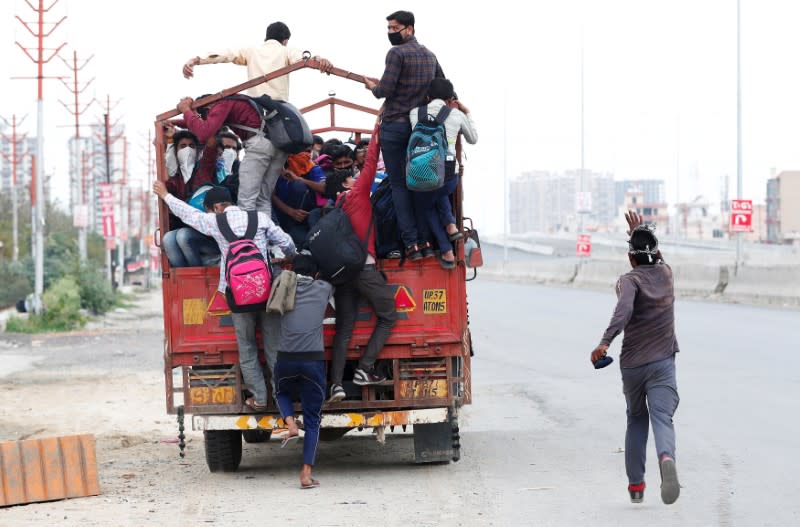 A migrant worker runs behind a truck as others try to board it to return to their villages after India ordered a 21-day nationwide lockdown to limit the spreading of coronavirus disease (COVID-19), in Ghaziabad