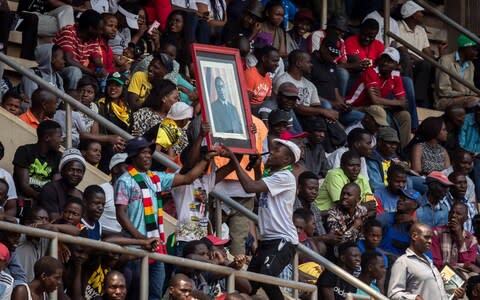 Mourners hold a portrait of Robert Mugabe - Credit: Ben Curtis/AP