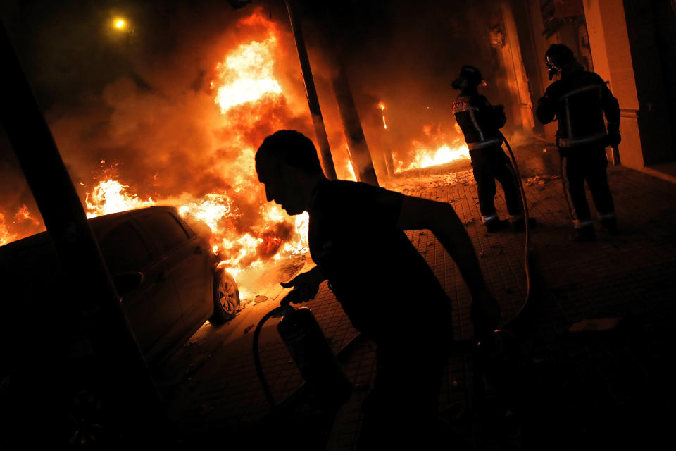 Firefighters and residents try to put out fires burning cars during clashes between protestors and police in Barcelona, Spain, Wednesday, Oct. 16, 2019. (Photo: Bernat Armangue/AP)