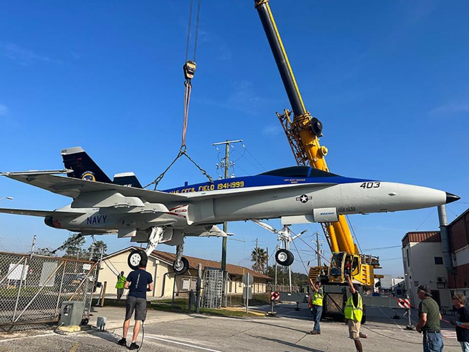 A restored F/A 18 Hornet jet is held by a crane during its journey from a Boeing hangar to a display spot at the National POW/MIA Memorial & Museum at Jacksonville's Cecil Commerce Center. The trip included being maneuvered over a gate.
