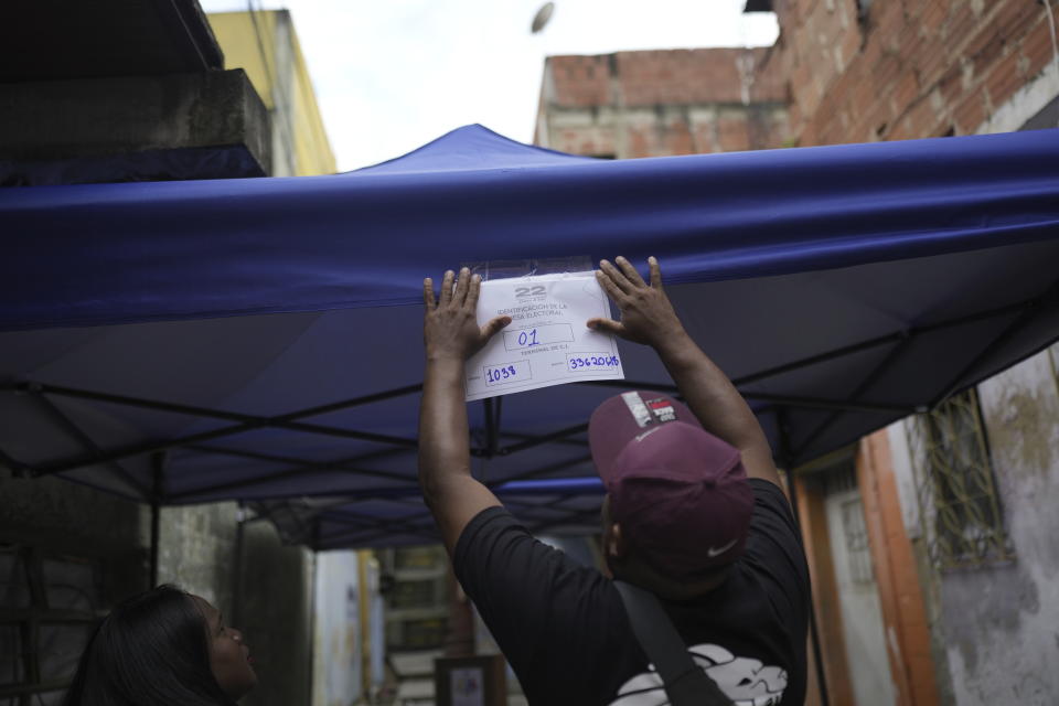 A resident puts identification on a voting station during the opposition presidential primary election in the Petare area of Caracas, Venezuela, Sunday, Oct. 22, 2023. The opposition will pick one candidate to challenge President Nicolás Maduro in 2024 presidential elections. (AP Photo/Ariana Cubillos)
