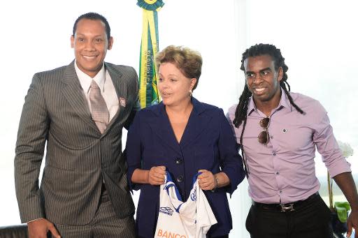 La Presidenta de Brasil, Dilma Rousseff (C), posa junto al futbolista Tinga (D) y al árbitro Marcio Chagas (I), ambos víctimas de actos racistas durante partidos de fútbol, en Brasilia, el 13 de marzo de 2014 (AFP/Archivos | EVARISTO SA)