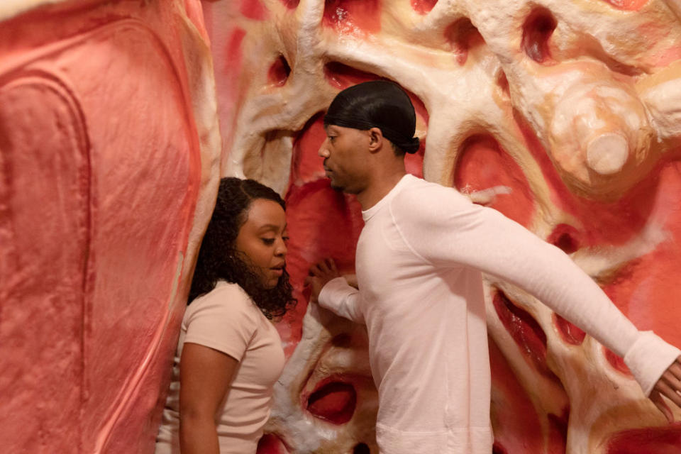 Two people walking through a textured, organic tunnel-like exhibit, expressing curiosity