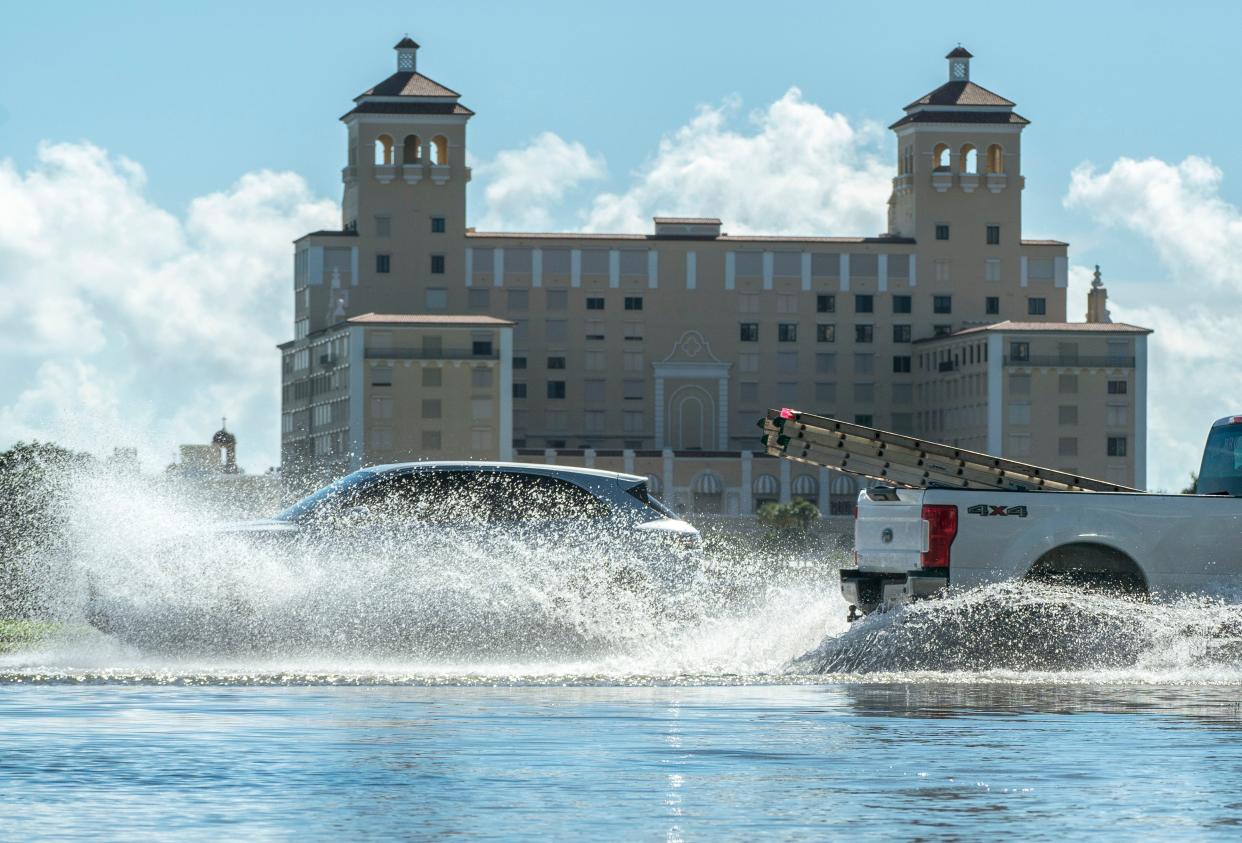 Motorists splash through the water along North Flagler Drive during king tide flooding in West Palm Beach in September, 2023.