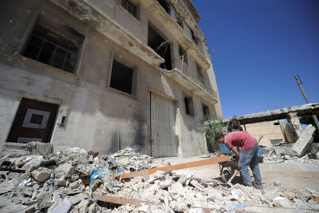 Workers clear debris outside of Kawai's battered factory to reopen it in Aleppo's Belleramoun Industrial Zone, Syria July 12, 2017. Picture taken July 12, 2017. REUTERS/Omar Sanadiki