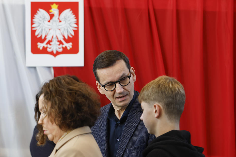 Poland's conservative ruling Law and Justice Prime Minister Mateusz Mazowiecki waits for his wife Iwona Morawiecka to cast her ballot during parliamentary elections in Warsaw, Poland, Sunday, Oct. 15, 2023. The outcome of Sunday's election will determine whether the right-wing Law and Justice party will win an unprecedented third straight term or whether a combined opposition can win enough support to oust it. (AP Photo/Michal Dyjuk)
