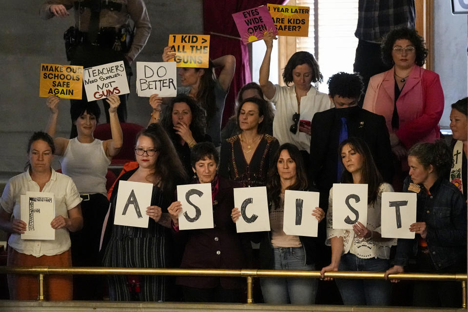 People hold signs in the gallery against a bill that would allow some teachers to be armed in schools during a legislative session in the House chamber Tuesday, April 23, 2024, in Nashville, Tenn. (AP Photo/George Walker IV)