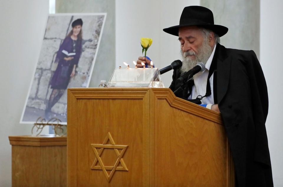 In this April 29, 2019 file photo, Yisroel Goldstein, Rabbi of Chabad of Poway, holds a yellow rose as he speaks at the funeral for Lori Kaye, who is pictured at left, in Poway, Calif.