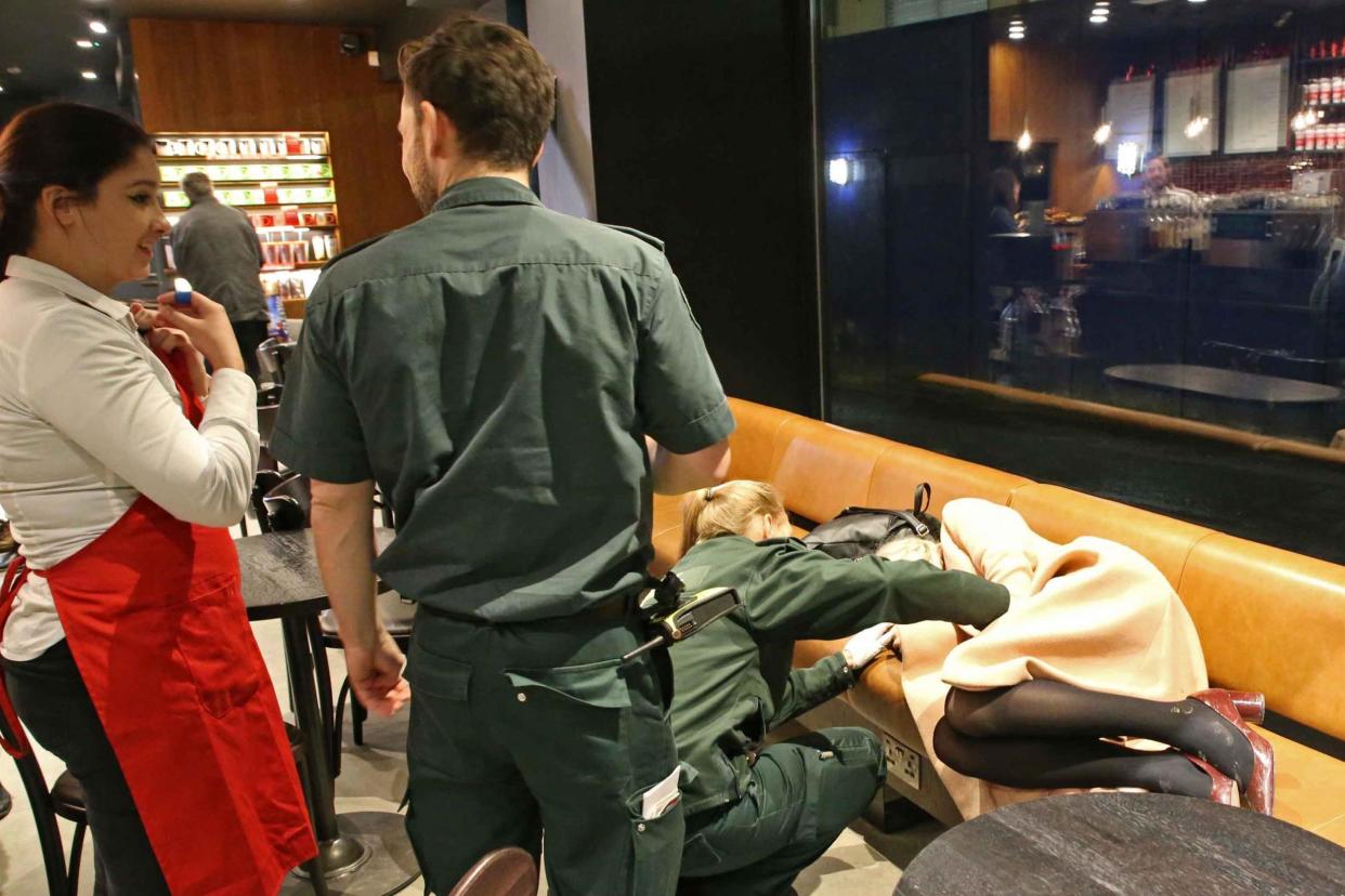 LAS staff treat a woman passed out in Starbucks, Charing Cross, around 10pm: NIGEL HOWARD ©