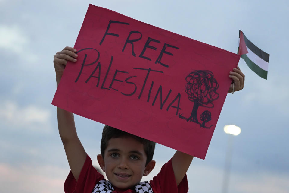 A boy from the Palestinian community shows a poster during Pro-Palestinian protest of the latest Israeli-Hamas war, outside the National Museum in Brasilia, Brazil, Friday, Oct. 20, 2023. (AP Photo/Eraldo Peres)