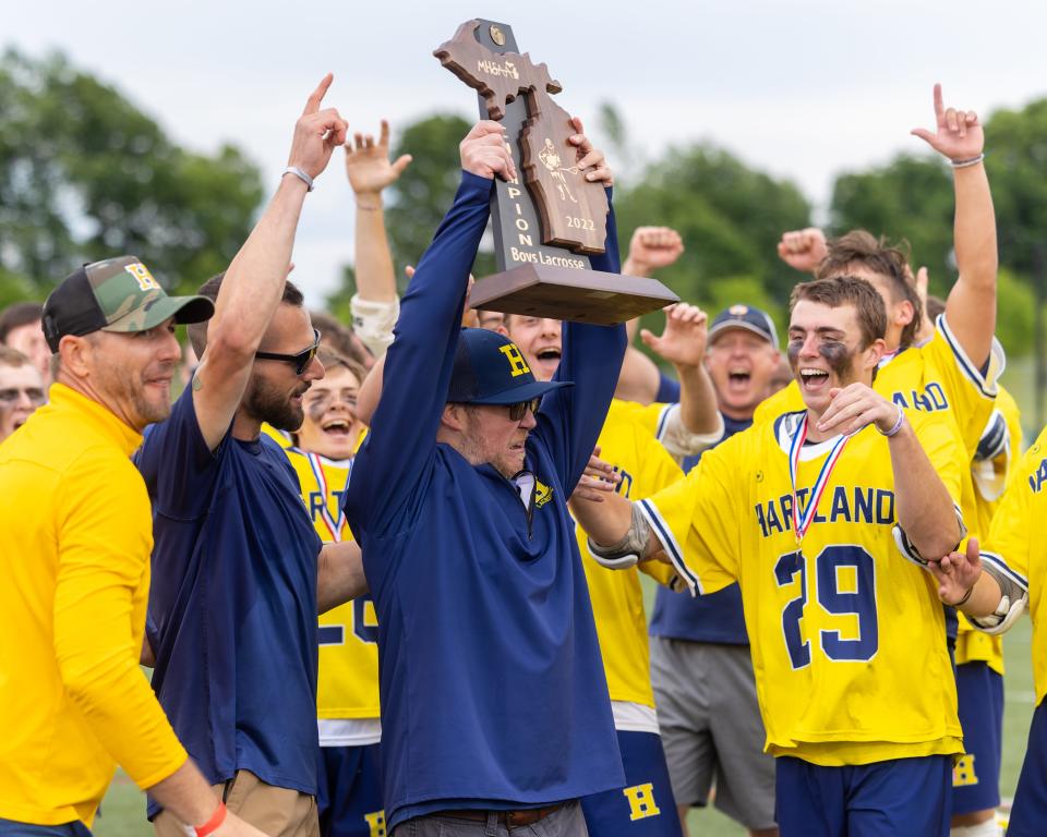 Hartland assistant coach Max Treanor hoists the state Division 1 boys lacrosse championship trophy on Saturday, June 11, 2022.
