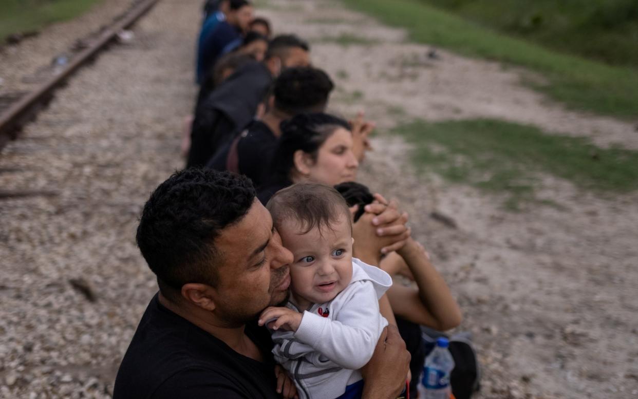 Asylum seekers wait to be taken to a processing facility in Texas after crossing the Rio Grande river on a raft to enter the United States from Mexico  - ADREES LATIF /REUTERS