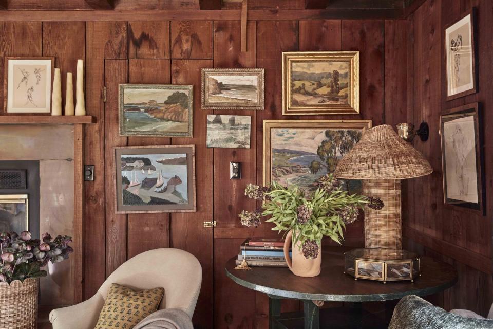 a room with a table and a lamp and pictures on the wall