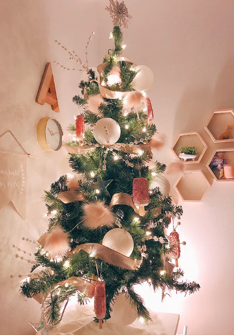 <p>Dieser hübsche Baum, den die Bloggerin Lauren Gardner aus L.A. für das Schlafzimmer ihrer Tochter gestaltet hat, ist mit kindersicheren Eis-am-Stiel-Dekoelementen (aus Plastik!), sowie einem rotgoldenen Band und rosa Pom-Pom-Zweigen geschmückt. Damit sorgt er garantiert für süße Träume. <br>(Foto mit freundlicher Genehmigung von Lauren Gardner) </p>