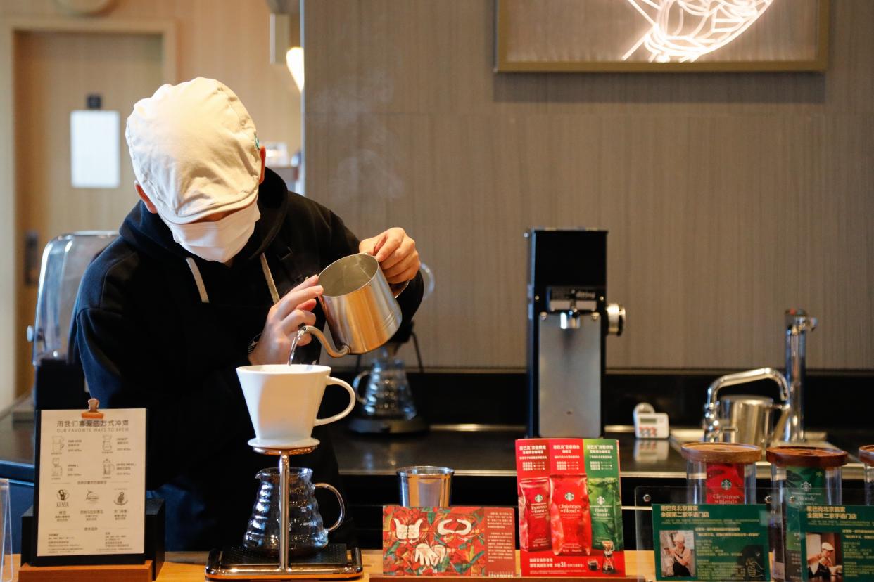 A barista brews coffee at the Starbucks Beijing Xitieying Wanda signing store in Beijing, capital of China, Nov. 23, 2023.  At the ongoing China International Supply Chain Expo CISCE, U.S. coffee giant Starbucks has attracted great attention through its coffee industrial chain and products.  Starbucks entered the Chinese mainland in 1999 and now operates more than 6,800 stores in over 250 cities in China.  In 2012, a Starbucks Farmer Support Center was set up in Pu'er of Yunnan Province, the first of its kind in Asia, to further bolster the local coffee farming community.  In 2017, Starbucks opened a Roastery location in Shanghai, its second after the one in Seattle in Washington state on the U.S. west Pacific.  This September, Starbucks opened a new coffee innovation park in Kunshan of Jiangsu Province, the company's largest manufacturing and distribution investment outside the United States. (Photo by Liu Mengqi/Xinhua via Getty Images)