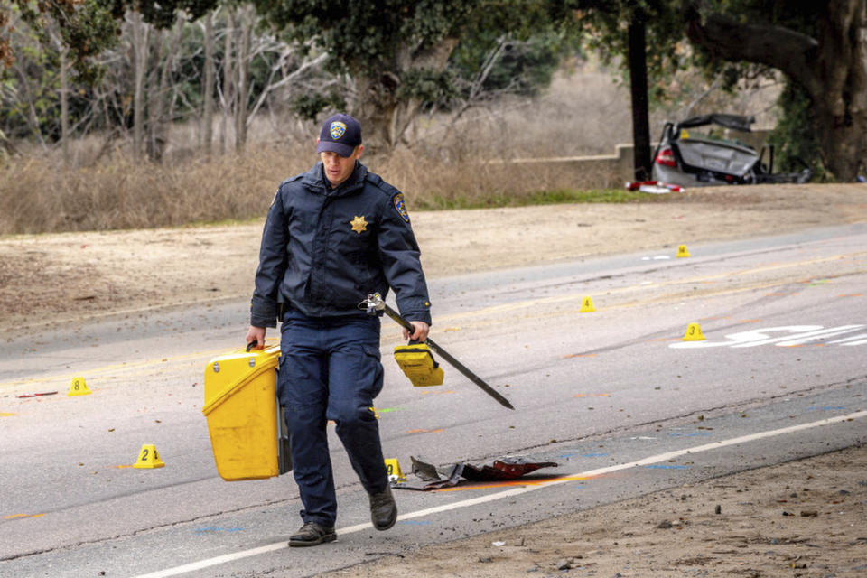 An officer with the California Highway Patrol's (CHP) Multidisciplinary Accident Investigation Team (MAIT) investigates the scene of a deadly crash in the Temescal Valley, south of Corona, Calif., Monday, Jan. 20, 2020. A Southern California driver intentionally rammed a Toyota Prius with several teenage boys inside, killing a few and injuring a few others before fleeing, authorities said Monday. (Watchara Phomicinda/The Orange County Register via AP)