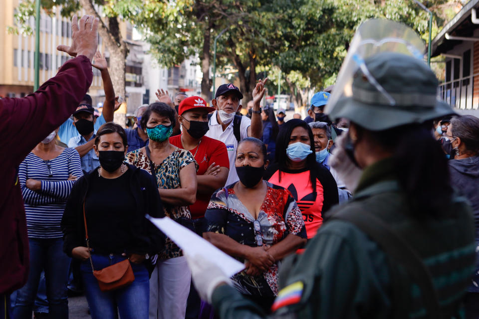 People argue with election officials at a polling station that did not open on time, during regional elections, in the San Agustin neighborhood of Caracas, Venezuela, Sunday, Nov. 21, 2021. Venezuelans go to the polls to elect state governors and other local officials. (AP Photo/Jesus Vargas)
