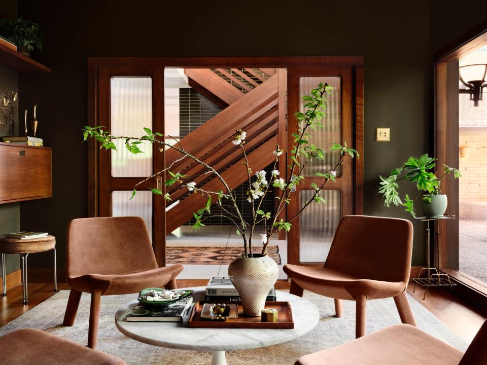 The custom-built floating staircase is visible from inside the library, which is painted in Wooded Acres by Magnolia.